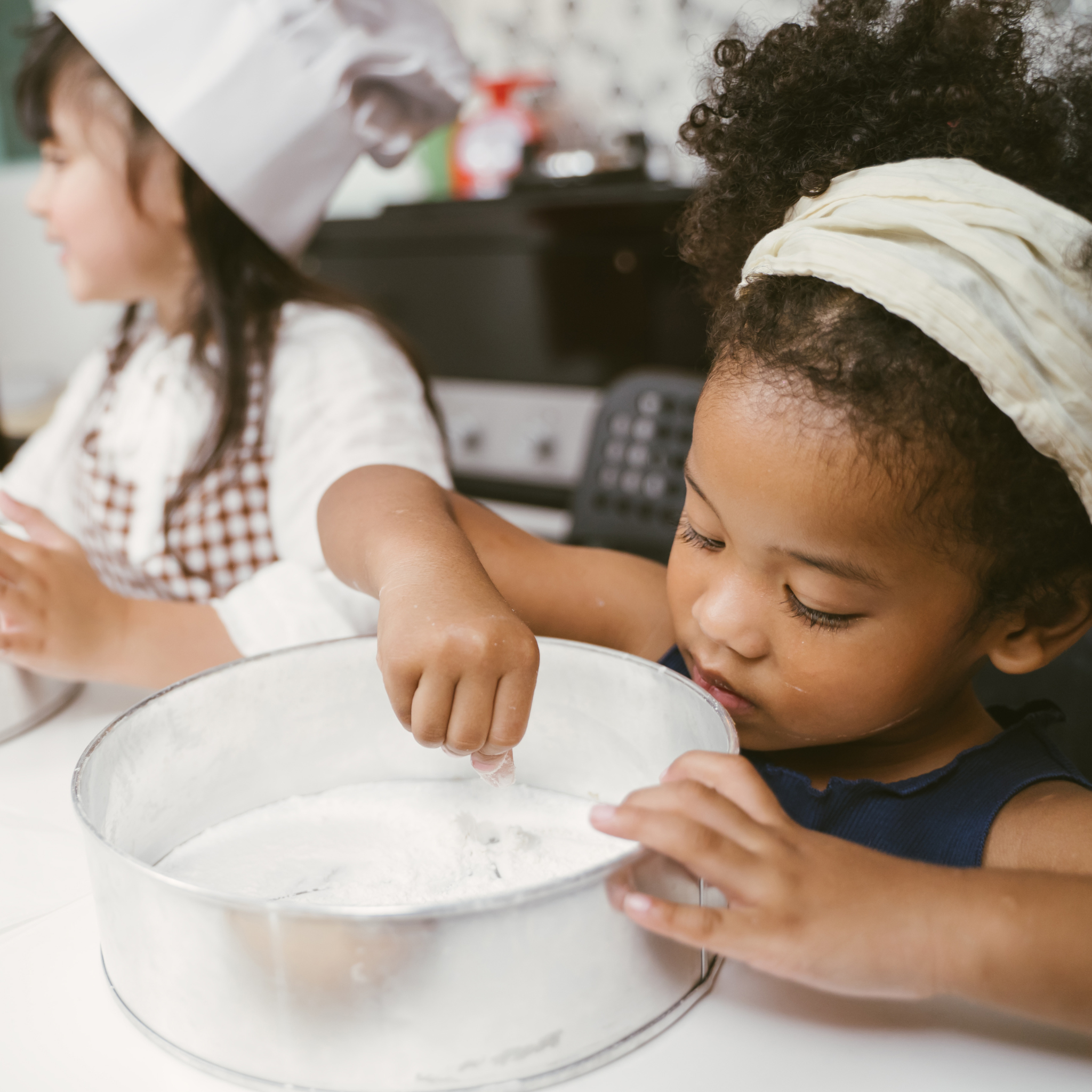 Child learning to pipe icing on cupcakes